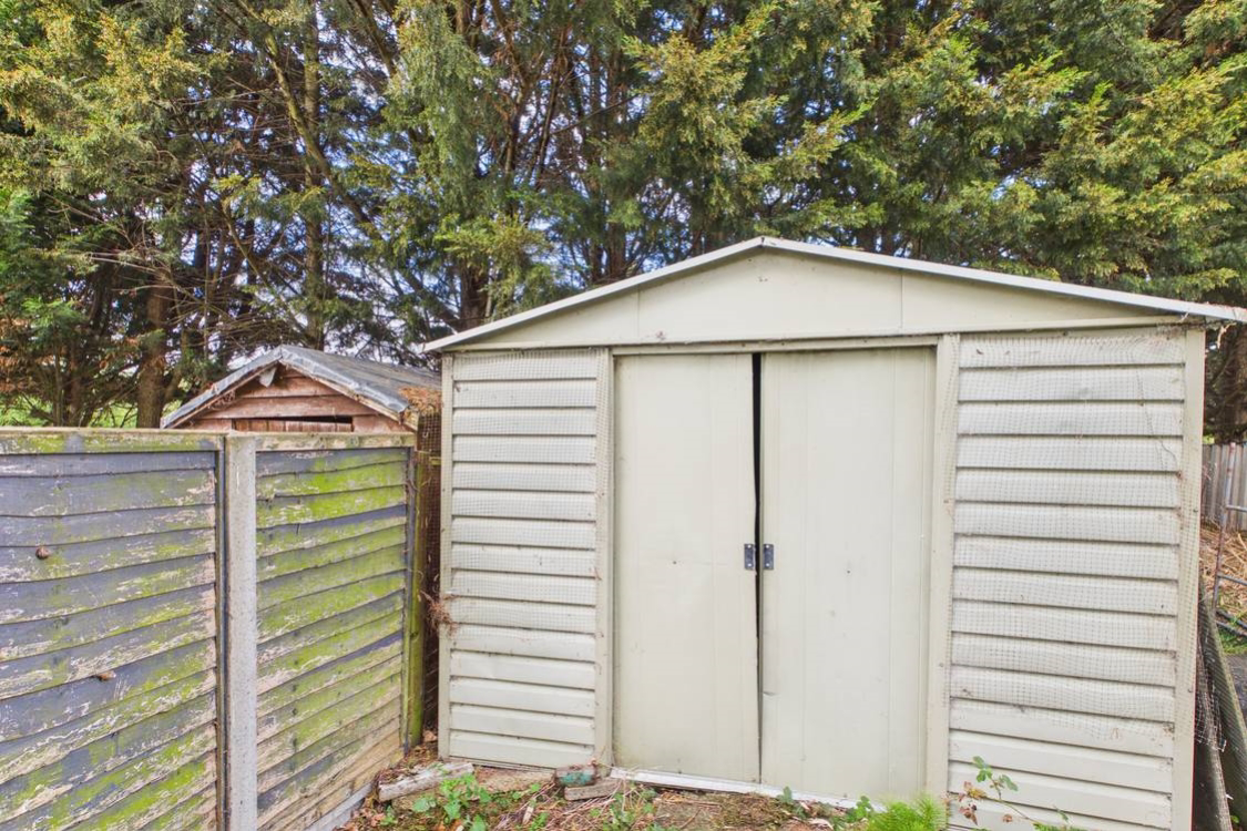 Large metal shed at the end of the garden to store garden furniture or toys